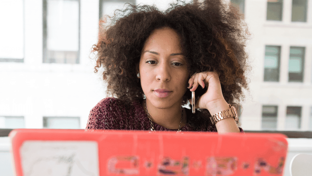 woman on phone looking at laptop